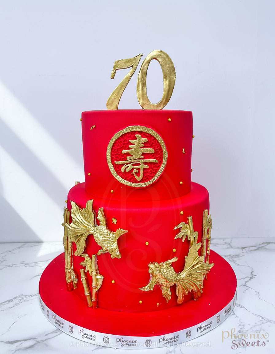 A two-tier red fondant cake with gold dragon decorations and a longevity symbol in gold on the top tier.